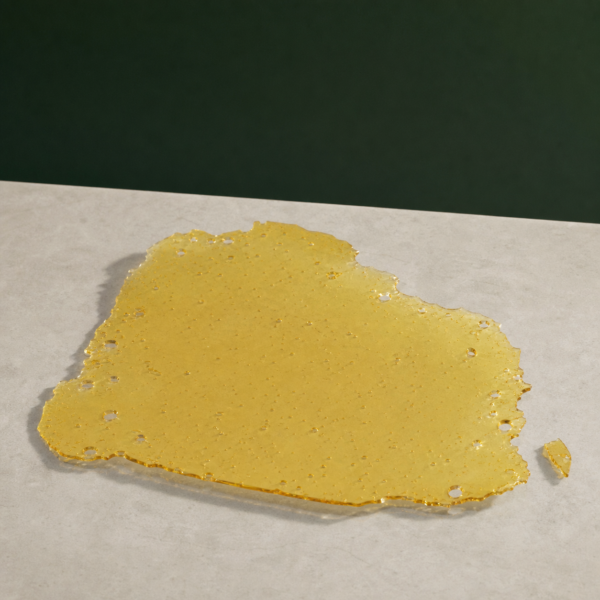 Good Giggles - Green Crack House Shatter 1g on a pale stone surface