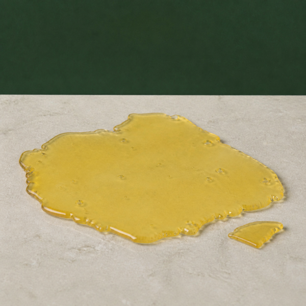 Good Giggles - Sour D House Shatter 1g on a pale stone surface