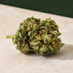 Green Crack cannabis flower on a pale stone studio surface