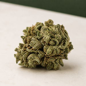 Mojo Melon cannabis flower side view on pale stone